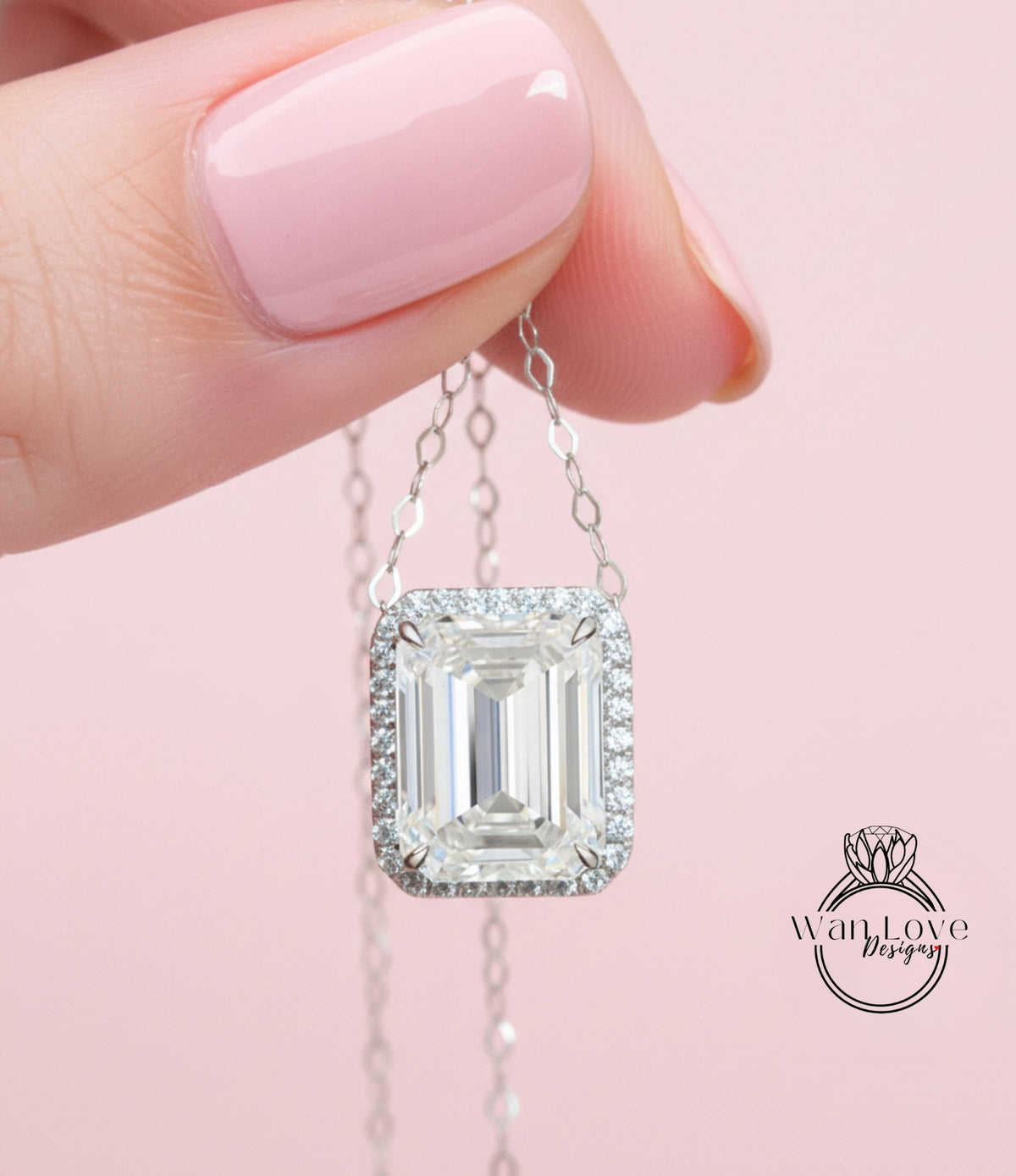 A hand holding a necklace with a large, clear gemstone pendant against a pink background.