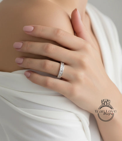 A close-up of a person's hand wearing a diamond ring, with a white blouse partially covering the hand.