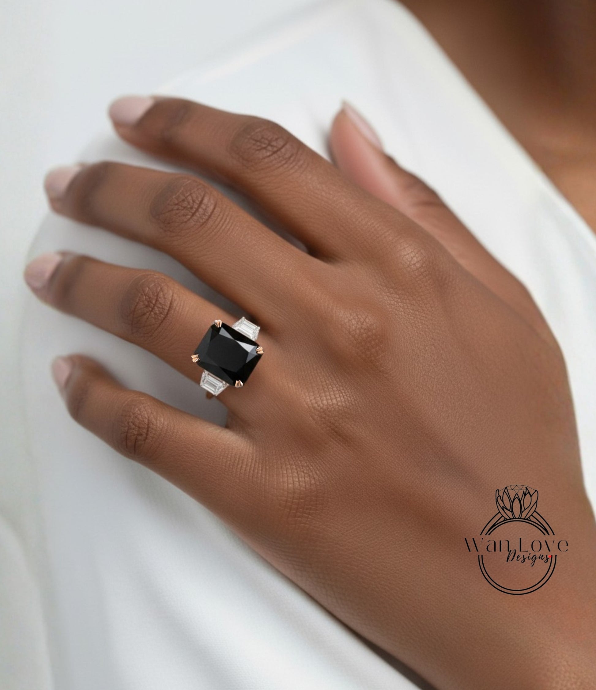 A close-up of a person's hand wearing a large black diamond ring with a white center stone.