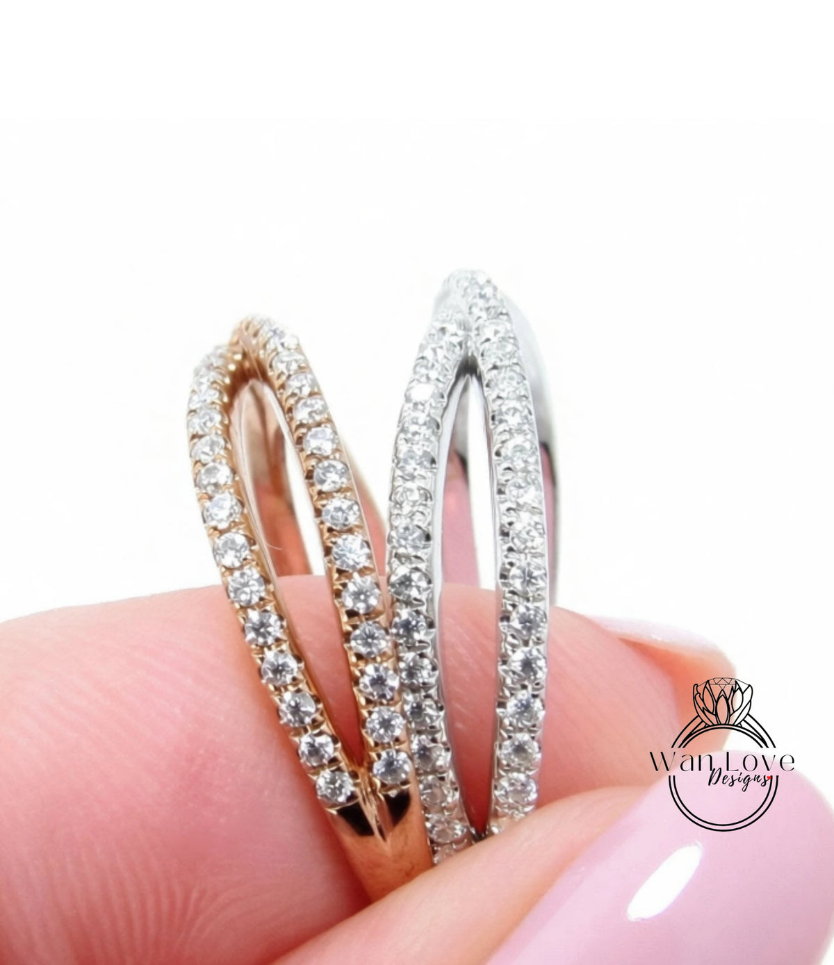 A close-up image of a person's hand holding two diamond-encrusted rings, one in gold and the other in silver.