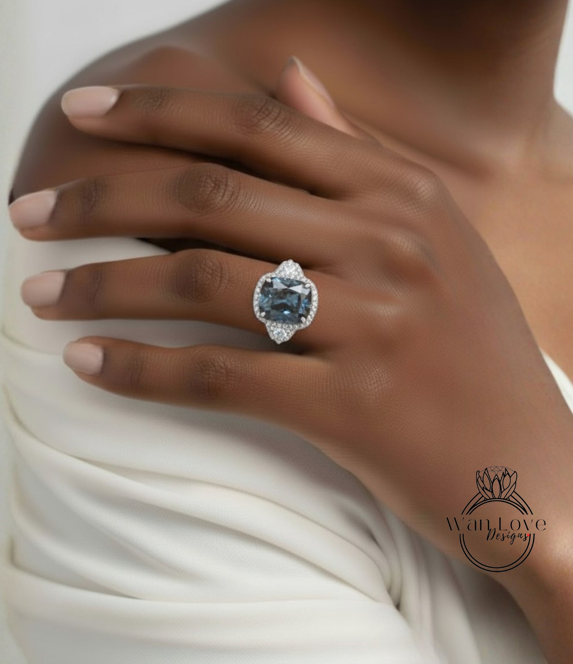 A close-up of a person's hand wearing a large, blue gemstone ring with a diamond center stone.