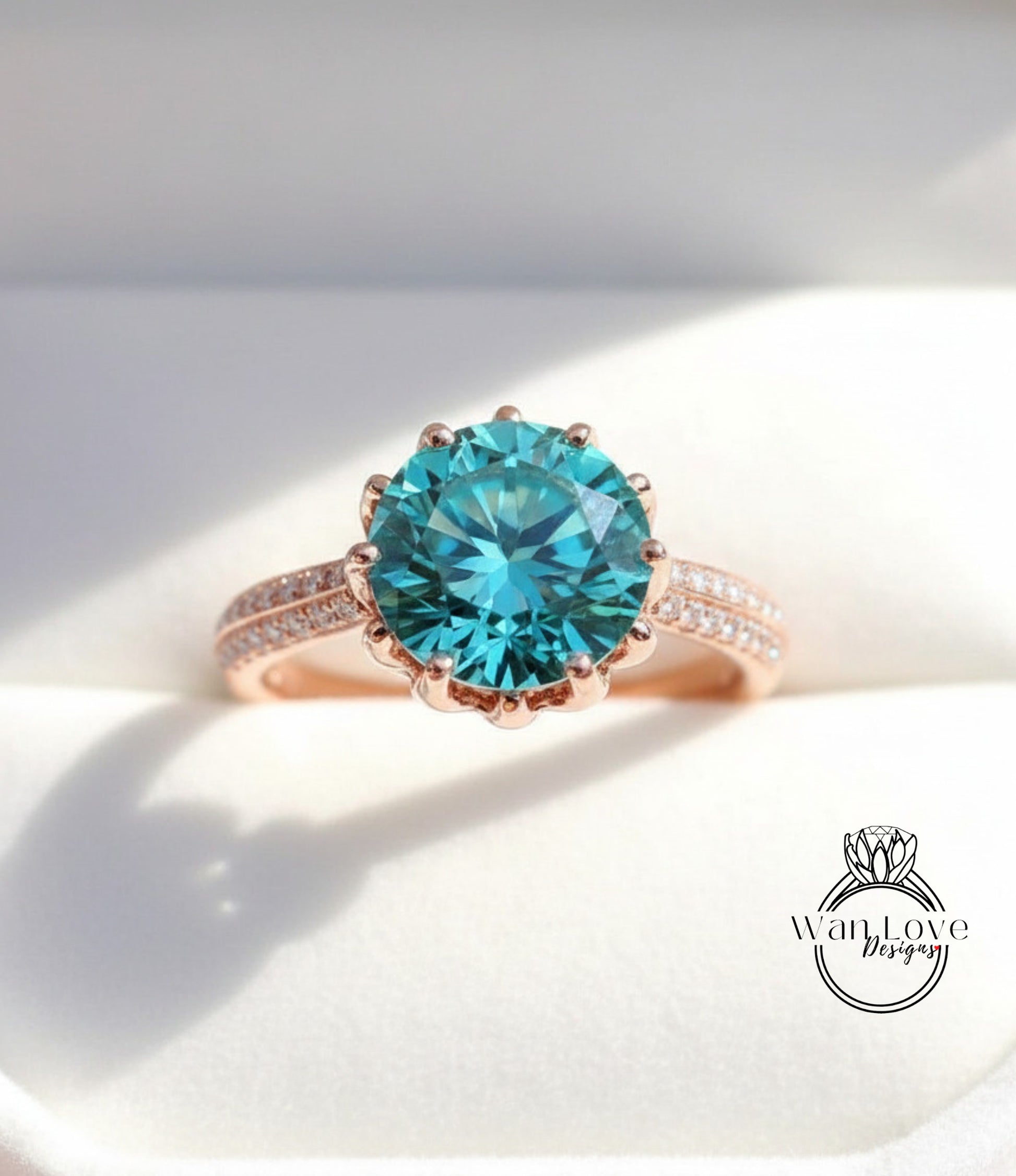 A close-up of a rose gold ring with a large, blue sapphire gemstone set in the center.