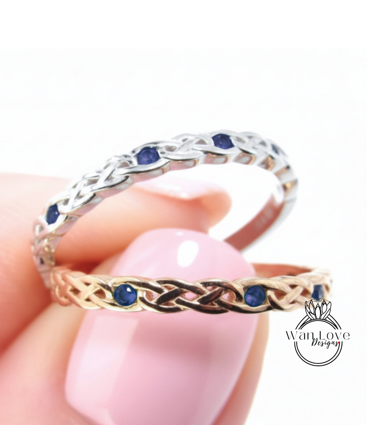A close-up of a hand holding two rings, one silver and one gold, with blue gemstones.