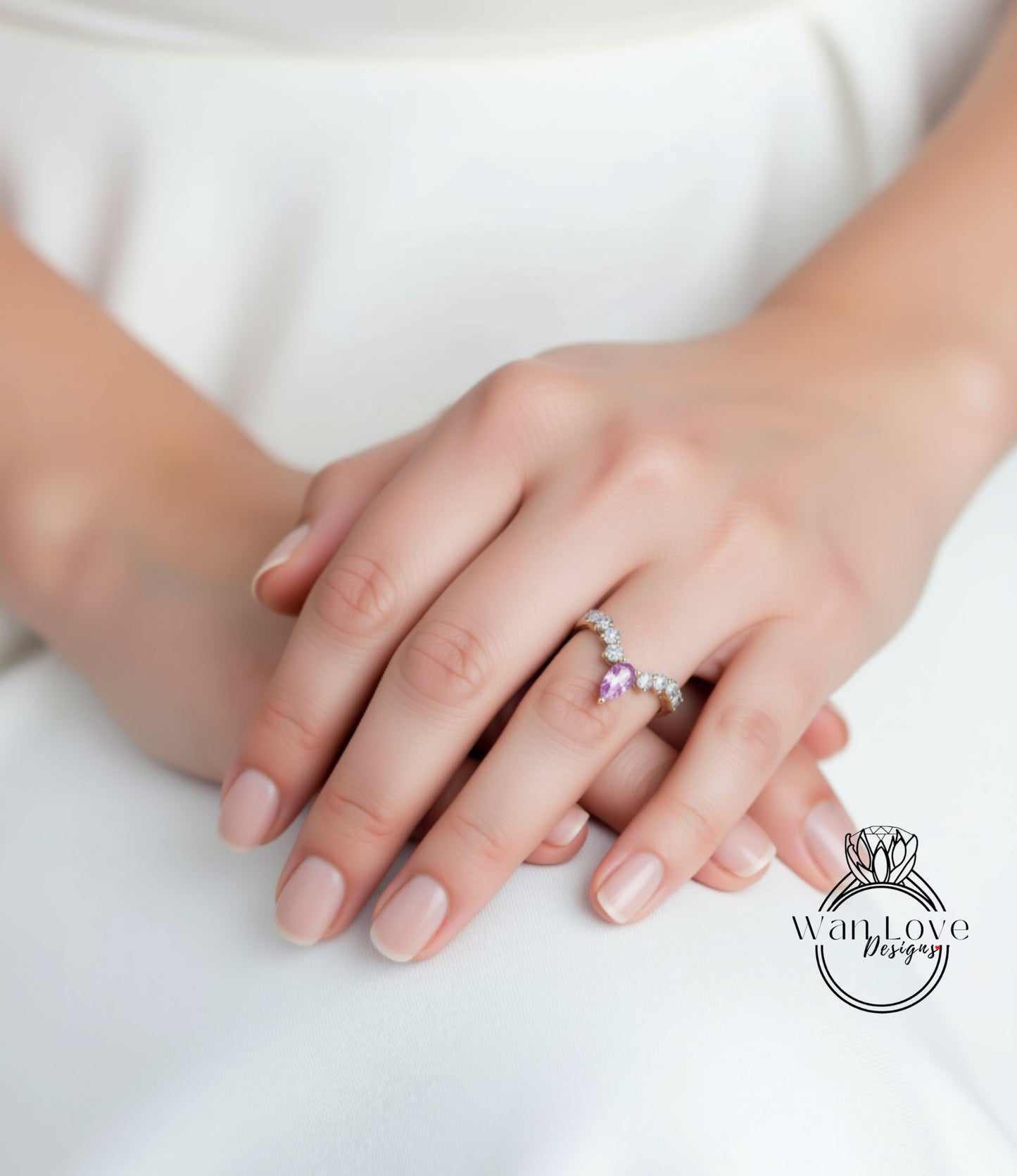 A close-up of a person's hands wearing a ring with a pink gemstone.