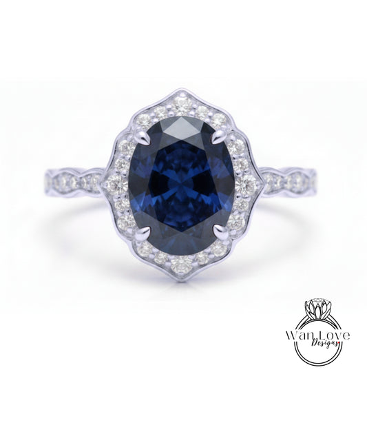 A close-up of a silver ring with a large oval-shaped blue gemstone at the center, surrounded by smaller diamonds.