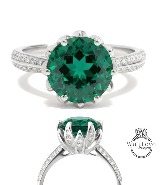 A stunning green gemstone ring with a large central stone surrounded by smaller stones, set in a silver band with a scalloped edge.