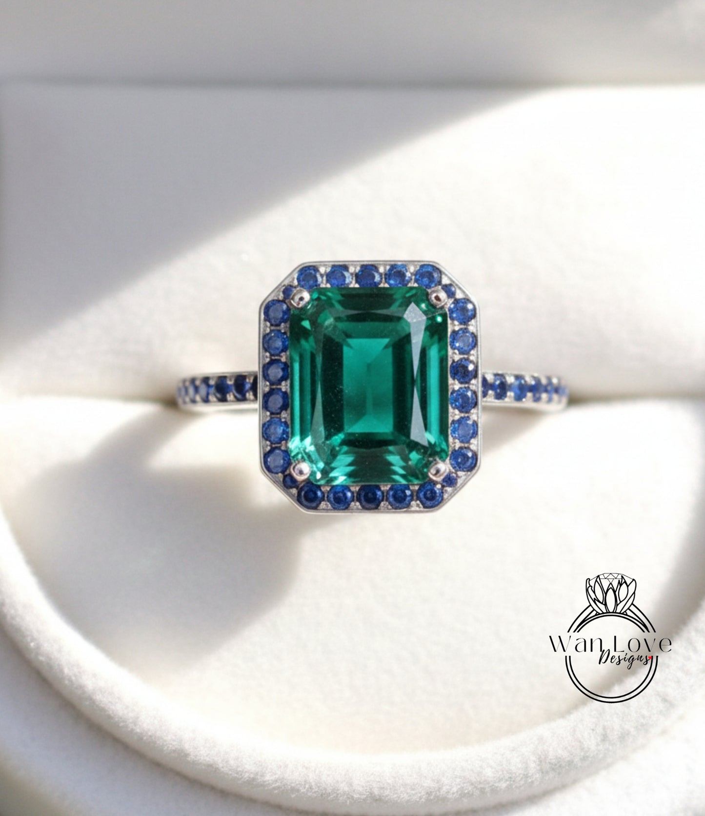 A close-up image of a silver ring with a large, green gemstone surrounded by smaller blue gemstones.