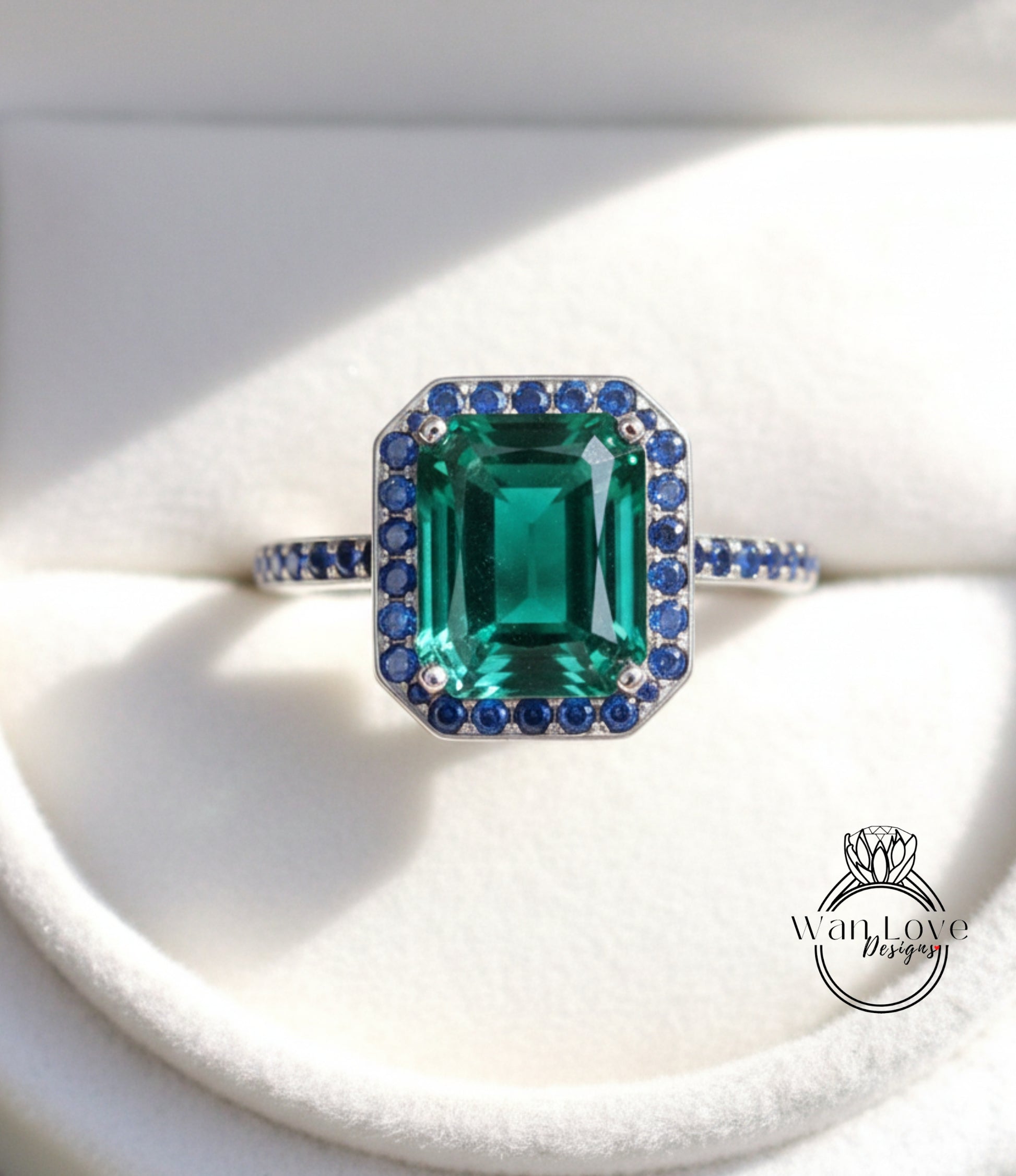 A close-up image of a silver ring with a large, green gemstone surrounded by smaller blue gemstones.