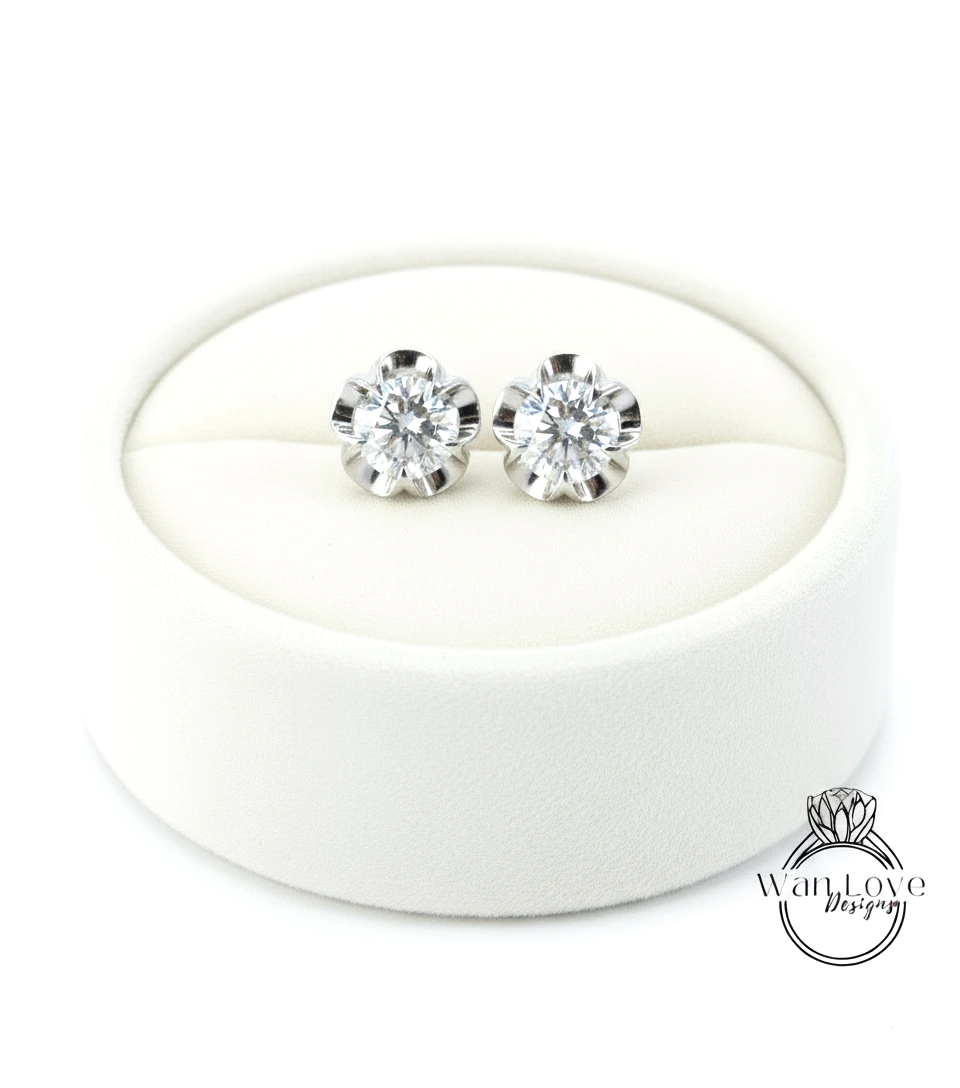 A pair of elegant diamond earrings displayed in a white jewelry box.