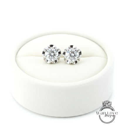 A pair of elegant diamond earrings displayed in a white jewelry box.