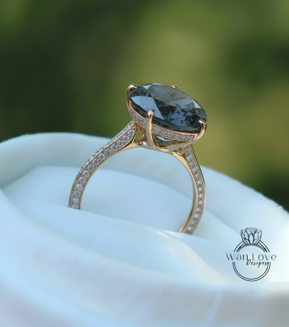 A large, dark blue diamond ring with a gold band and small diamonds set in it, displayed on a white cloth.