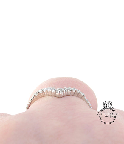A close-up view of a person's hand wearing a diamond ring with a heart-shaped design.