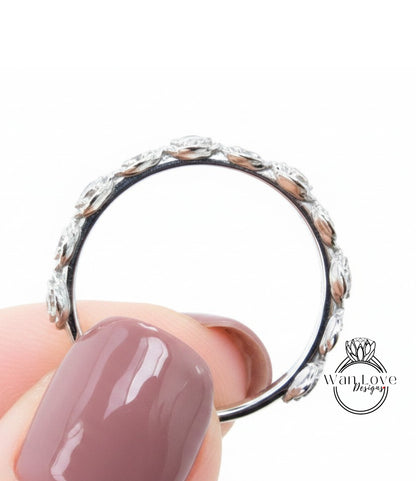 A close-up of a person's hand holding a silver ring with a floral design.