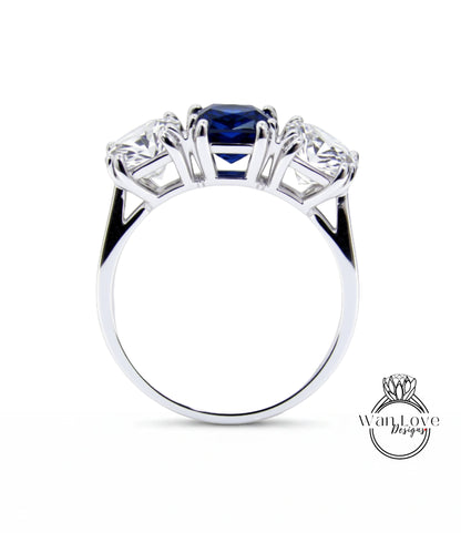 A silver ring with three gemstones, including a blue gemstone, set in a three-prong design.