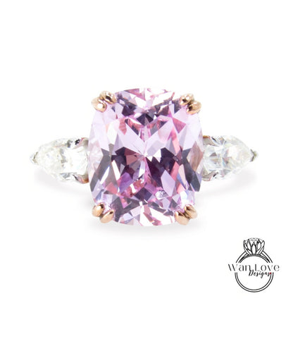 A large, oval-shaped pink gemstone set in a ring, with two smaller diamonds on either side.