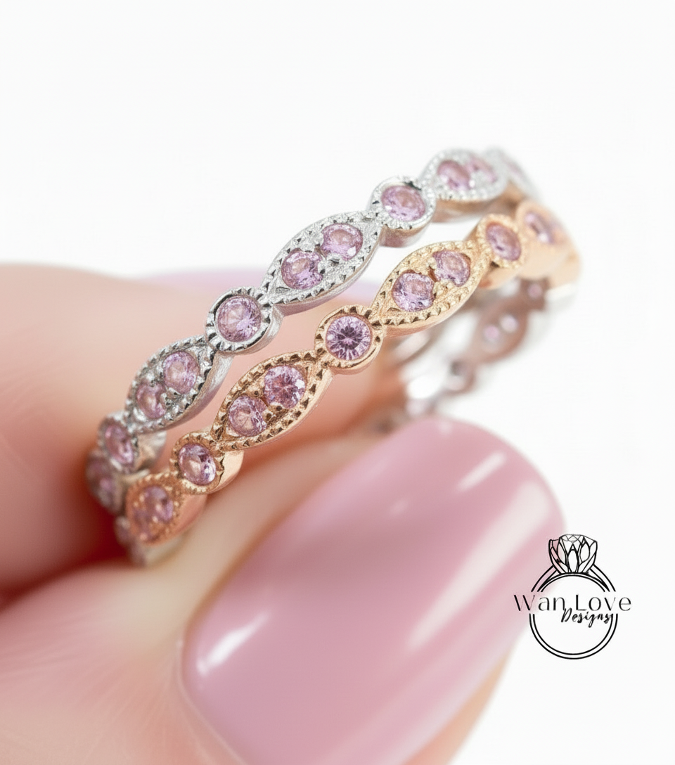 A close-up of a person's hand wearing a ring with pink gemstones.