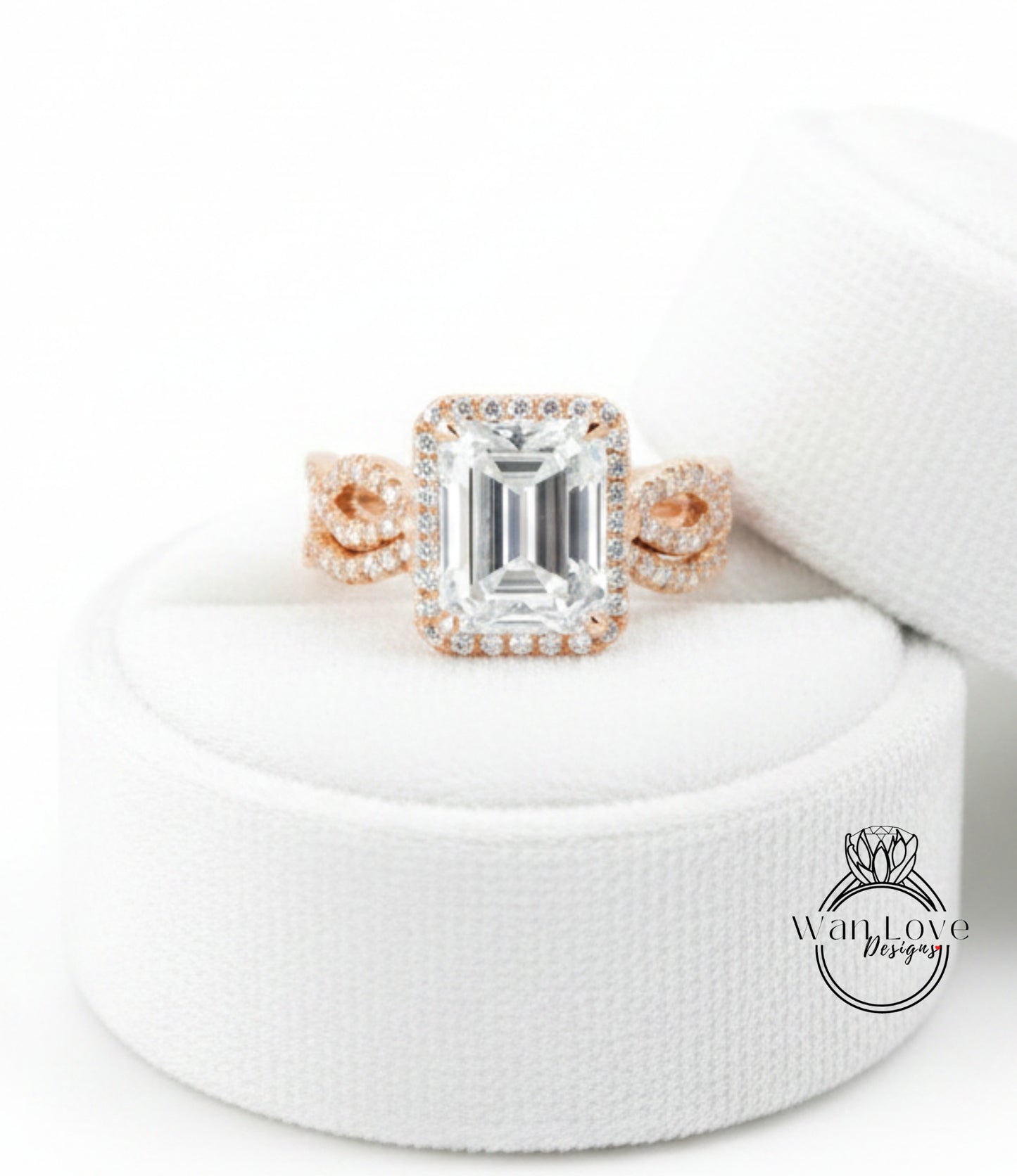 A large, clear gemstone ring with a halo of smaller diamonds around the center stone, displayed on a white fabric background.