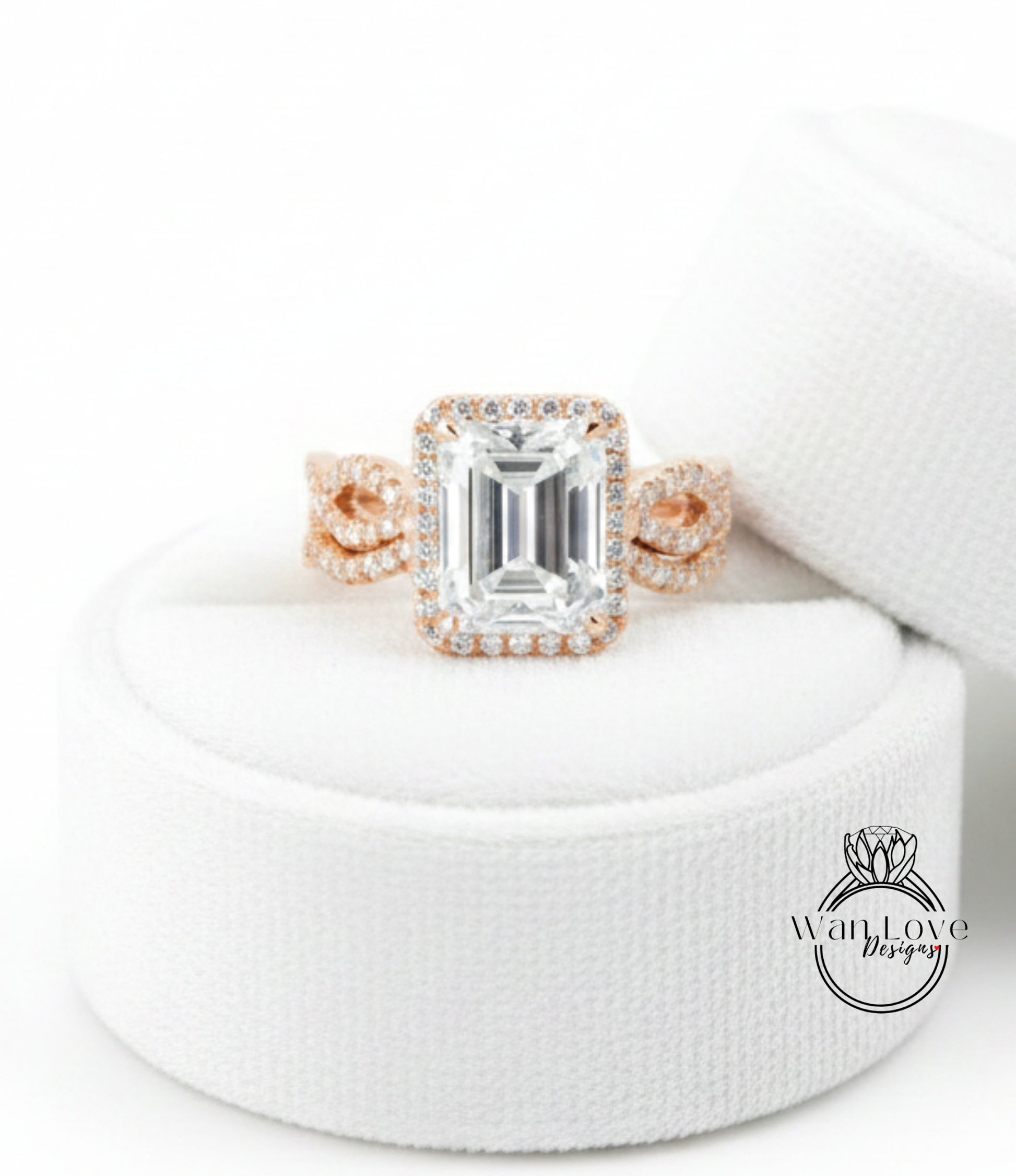 A large, clear gemstone ring with a halo of smaller diamonds around the center stone, displayed on a white fabric background.