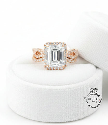 A large, clear gemstone ring with a halo of smaller diamonds around the center stone, displayed on a white fabric background.