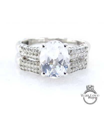 A close-up view of a diamond engagement ring with a large, clear gemstone set in a silver band adorned with small diamonds.