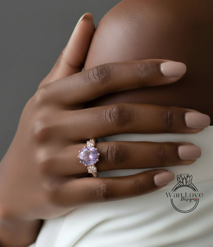 A close-up of a hand wearing a gold ring with a large purple gemstone, resting on a white fabric.