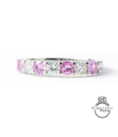 A silver ring with a row of pink and clear gemstones, including diamonds and rubies, set in a band.