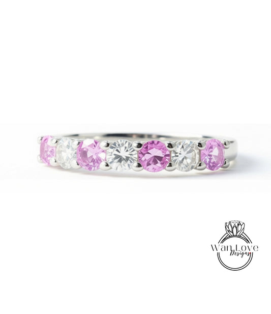 A silver ring with a row of pink and clear gemstones, including diamonds and rubies, set in a band.