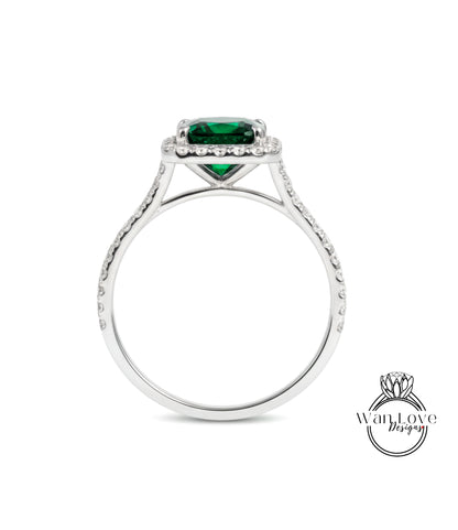 A silver ring with a large green gemstone, likely a diamond, set in the center.