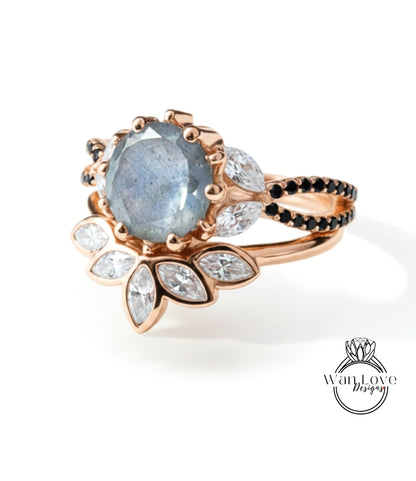 A rose gold ring with a large blue gemstone and smaller white and black gemstones set in a floral design.