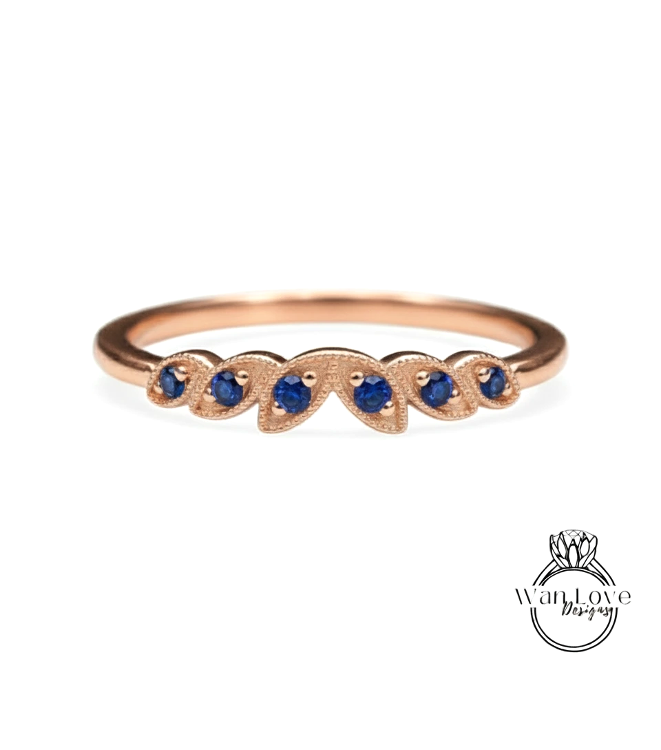A rose gold ring with a leaf-shaped design and blue gemstones.