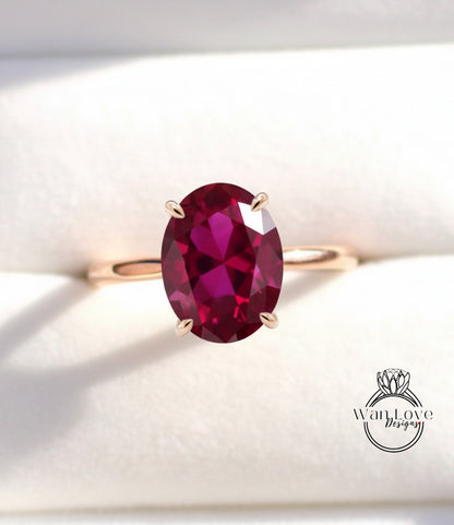 A close-up image of a gold ring with a large, deep red gemstone, likely a garnet, set in the center of the band.