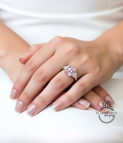 A close-up of a person's hand wearing a large, pink diamond ring.