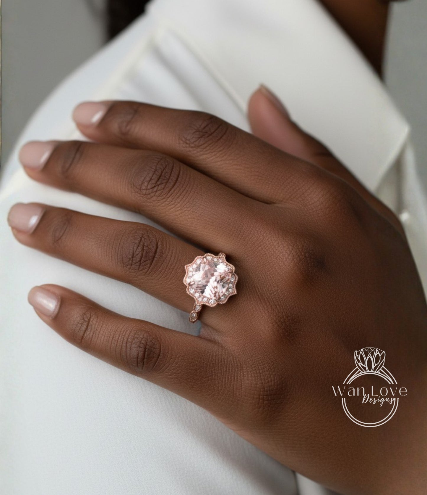 A close-up of a hand wearing a large, pinkish-colored diamond ring on the ring finger.