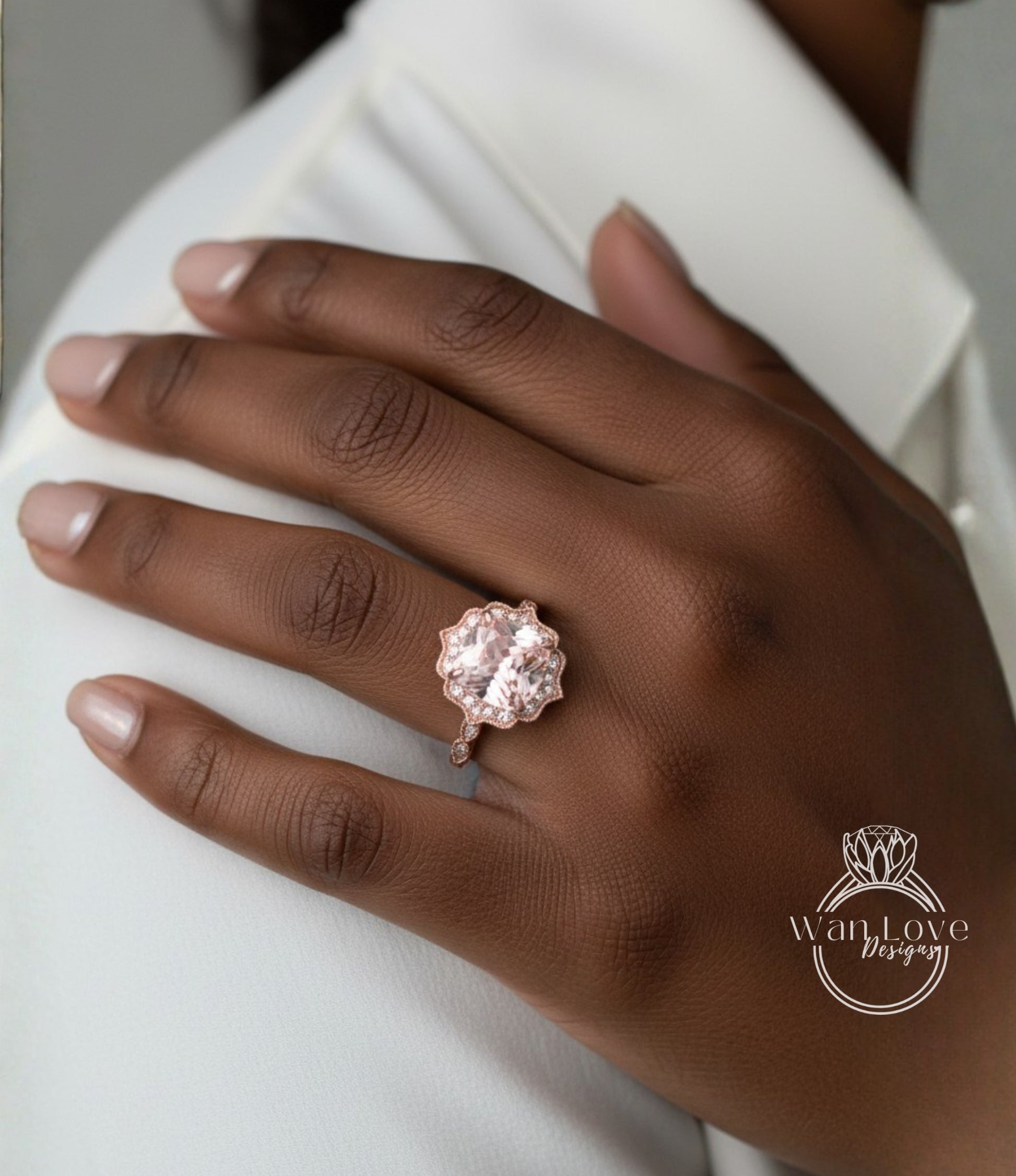 A close-up of a hand wearing a large, pinkish-colored diamond ring on the ring finger.
