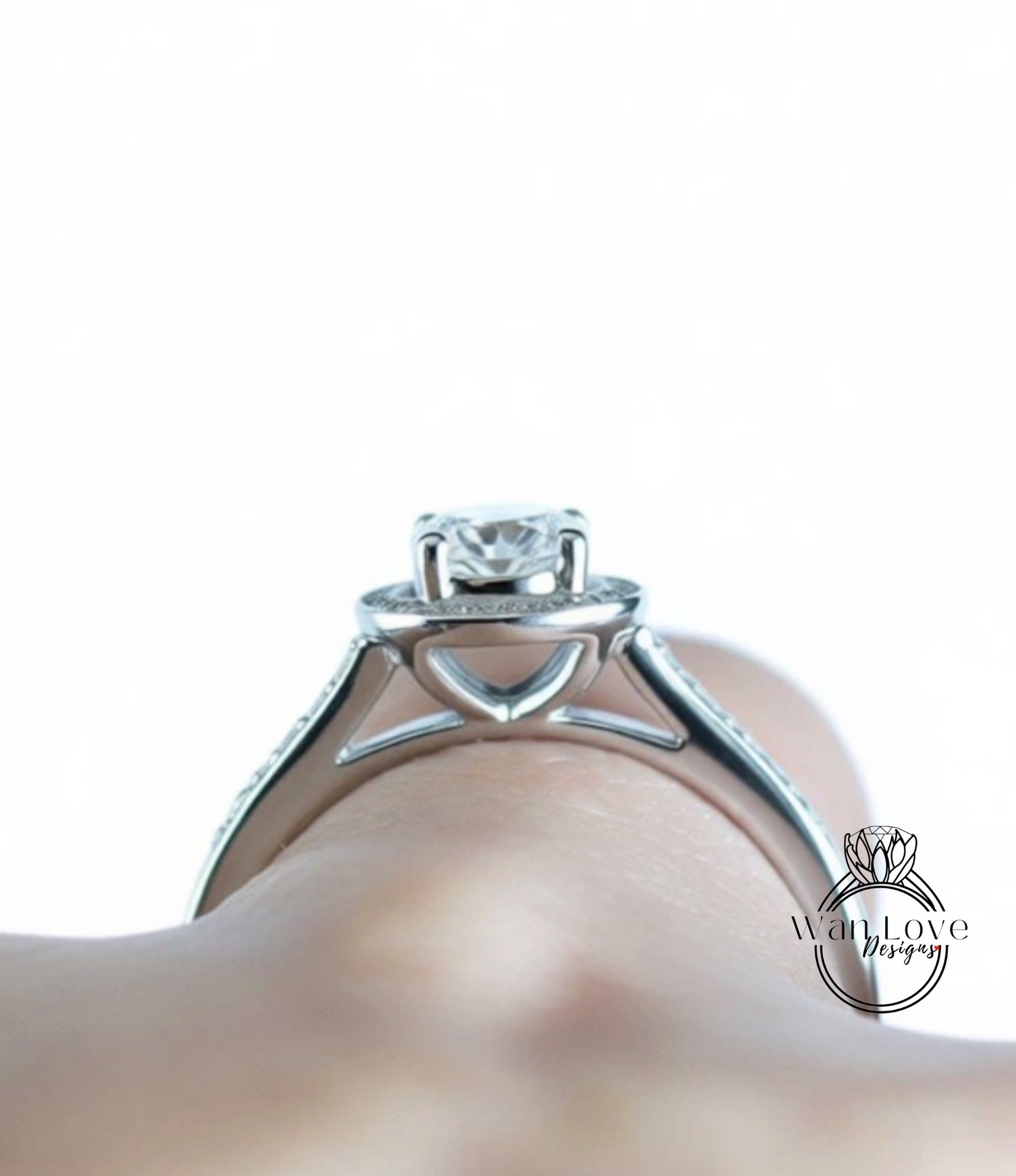 A close-up view of a silver engagement ring on a person's hand.