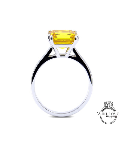 A silver ring with a large yellow gemstone, likely a diamond, set in the center of the band.