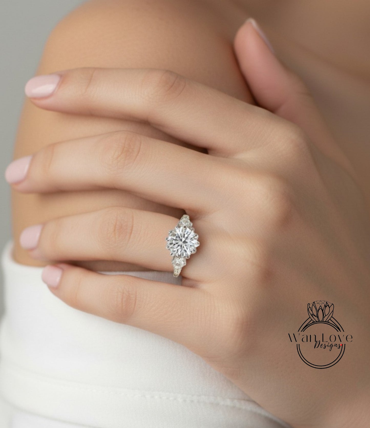 A close-up of a person's hand wearing a diamond engagement ring on the ring finger.