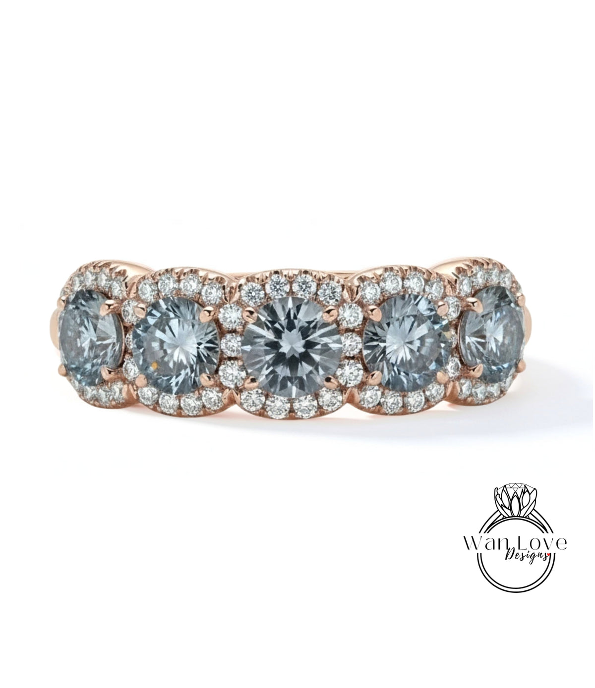 A ring with a row of four large, clear gemstones set in a halo of smaller diamonds, all set in a rose gold band.