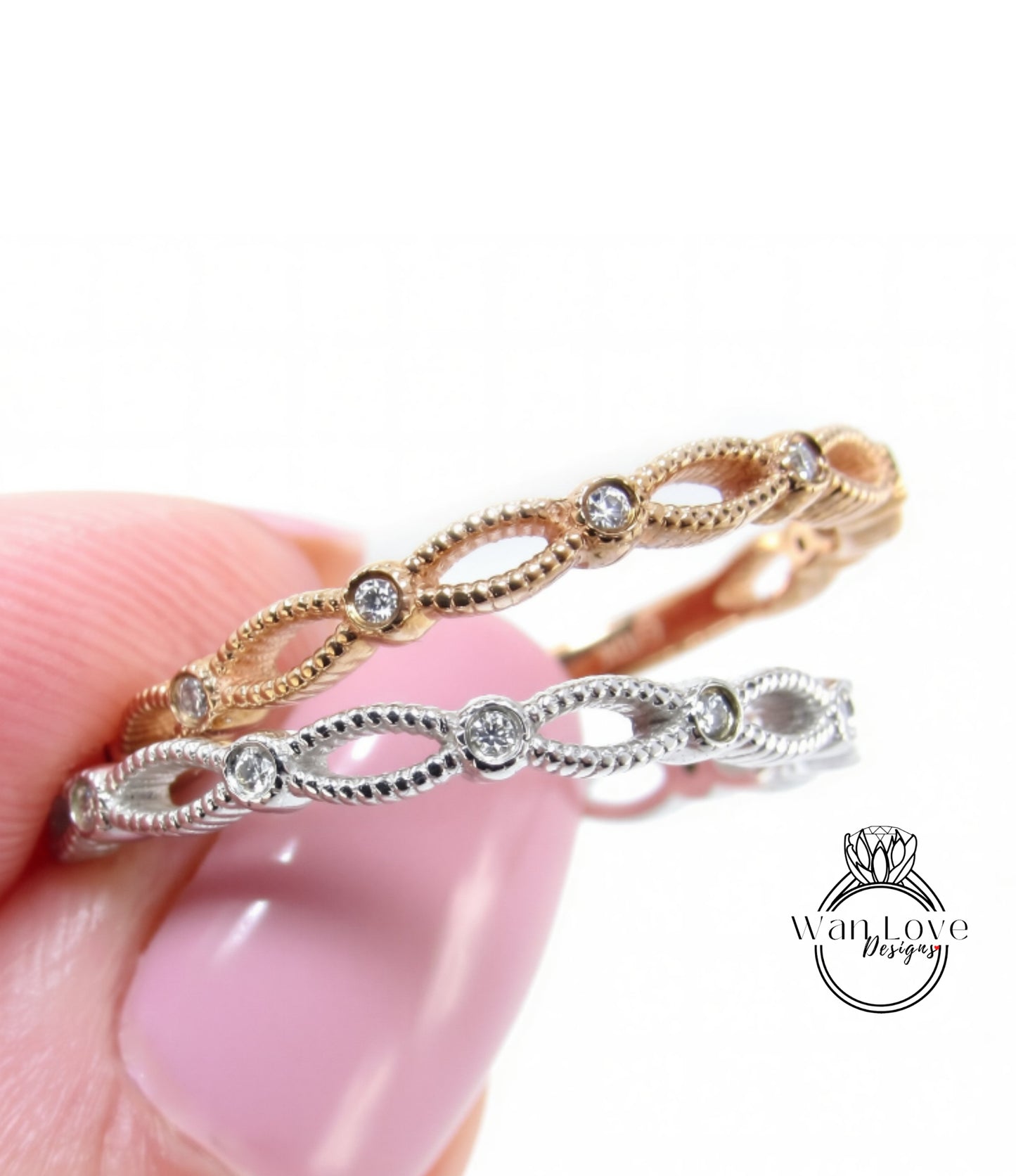 A close-up of a person's hand holding a ring with a delicate, intricate design featuring small diamonds.