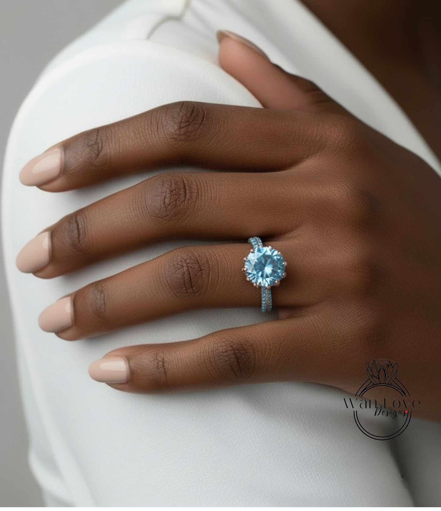 A close-up of a person's hand wearing a blue diamond ring on the ring finger.