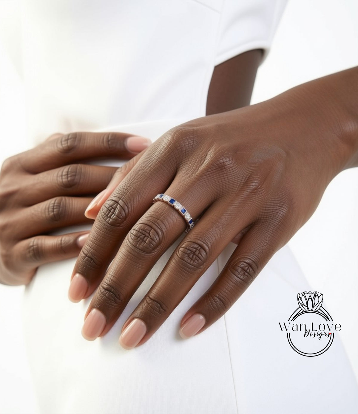 A close-up of a person's hand wearing a ring with a row of blue gemstones.