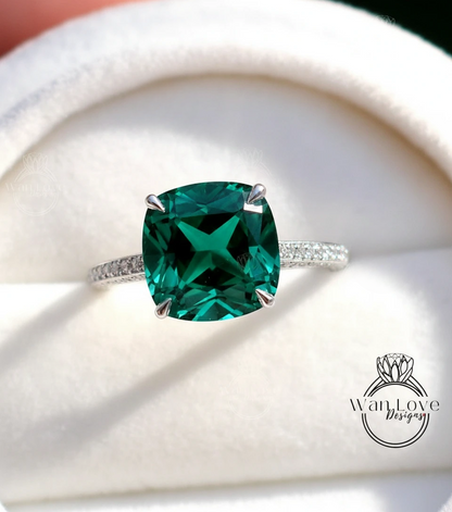 A close-up image of a diamond engagement ring with a large, green gemstone set in a silver band.