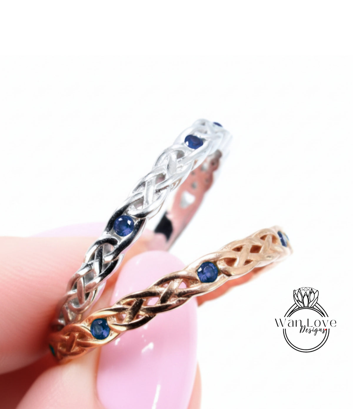 A hand holding two rings with intricate designs and blue gemstones.