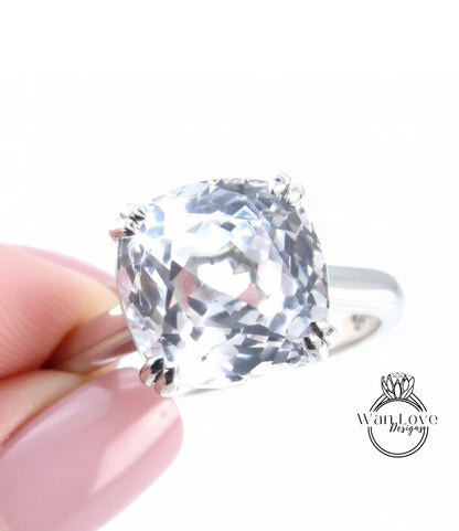 A close-up image of a person's hand holding a large, clear gemstone ring.