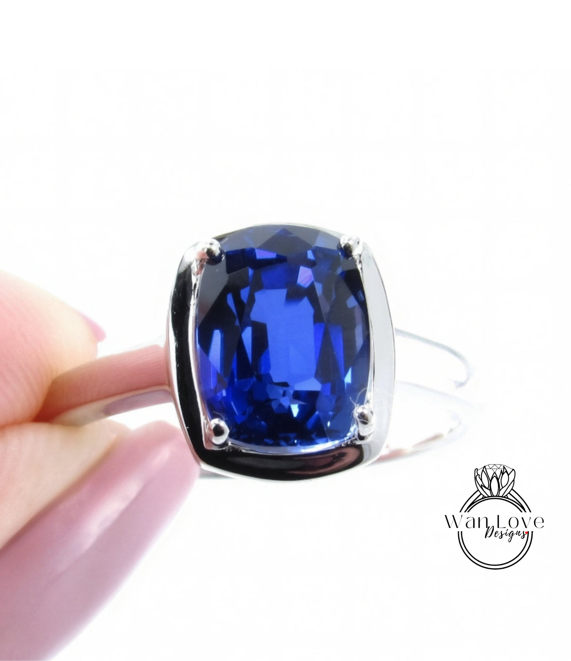 A hand holding a silver ring with a large blue gemstone, likely a sapphire or blue topaz.