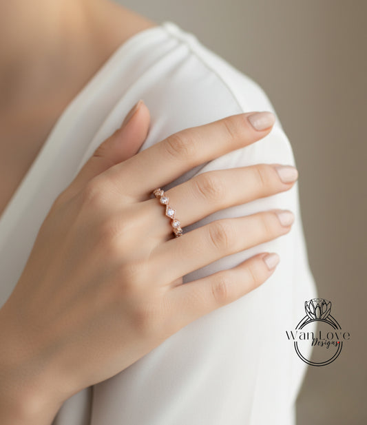 A close-up of a person's hand wearing a delicate gold ring with a row of small diamonds.