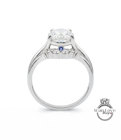 A silver engagement ring with a large central diamond and a smaller blue gemstone.