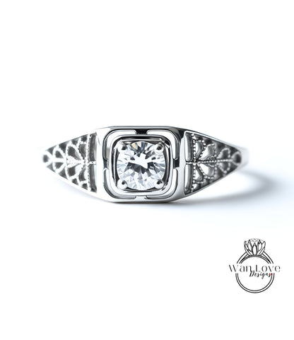 A close-up of a silver ring with a large central diamond surrounded by intricate floral designs on either side.