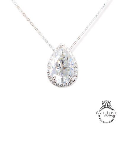 A close-up view of a diamond pendant necklace with a large, clear pear-shaped diamond set in a halo of smaller diamonds.