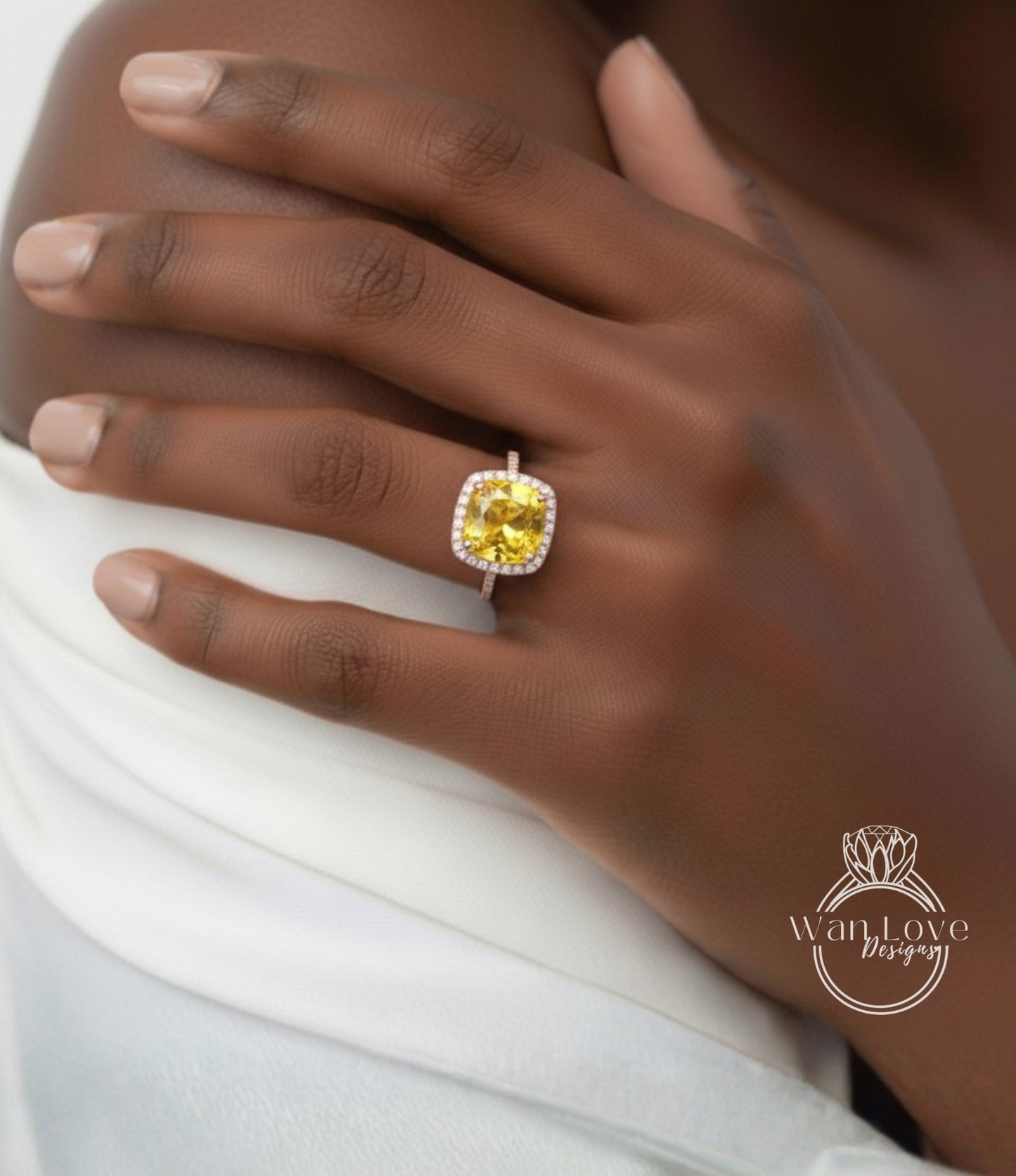 A close-up of a person's hand wearing a yellow diamond ring on the ring finger.